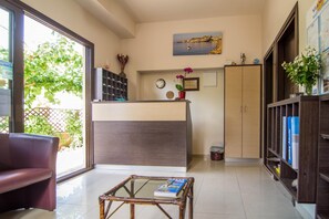 Ein modernes Wohnzimmer mit Glastisch, einer Couch, einer Küchenzeile mit Theke und einem Bücherregal.