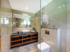 Ein modernes Badezimmer mit einem großen Spiegel, einem freistehenden Waschbecken, einer Glaskabine für die Dusche und einer Holz-Waschkommode.