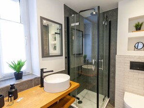 A modern bathroom with a glass-enclosed shower, a round white sink, and a wooden vanity. - Holiday Apartment With 2 Bedrooms (Braunlage)