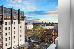 A high-rise building with multiple balconies, a river in the background, and a clear sky. - On the Boulevard - Styled 1BR with Views (Melbourne)