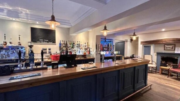 A bar area with a counter, shelves of bottles, and a fireplace in the background. - Standard Single Room - Shared (Derby)
