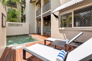 Ein Poolbereich mit Liegestühlen, einem kleinen Pool und einer Holzterrasse.
