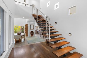 A modern staircase with wooden steps and metal railings, leading to an upper floor. - Belle Escapes Cairns One Condo with Private Pool (Cairns)