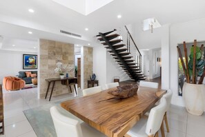 Ein moderner Essbereich mit einem Holztisch, weißen Stühlen und einer Wendeltreppe.