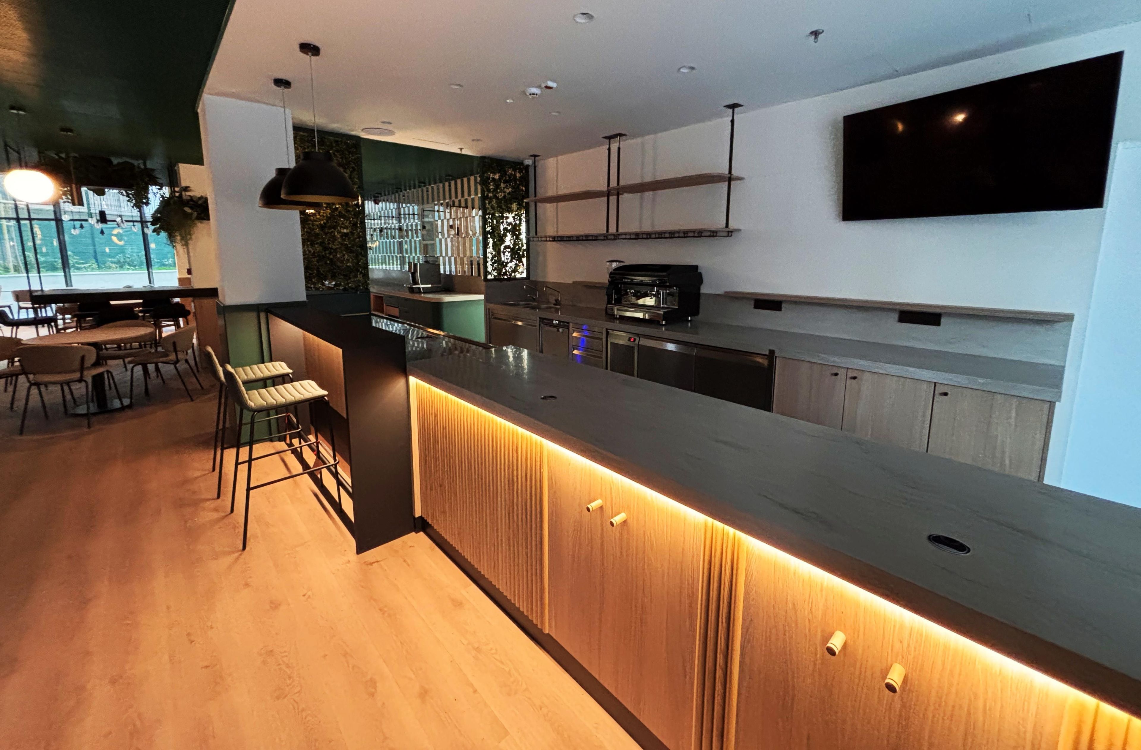 Una cocina moderna con una isla grande, taburetes de bar y una cafetera integrada.