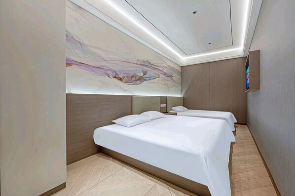A modern hotel room with a large abstract painting on the wall, a bed with white linens, a bedside table, and a flat-screen TV mounted on the wall.
