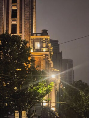 A nighttime view of a building with illuminated windows and a street lamp in the foreground.