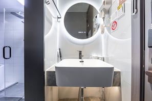 A modern bathroom with a white sink, a round mirror, and a towel rack. - JINOUWANGUO HOTEL (Huangpu District)