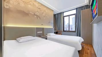 Une chambre d’hôtel avec deux lits, une grande fenêtre et un téléviseur fixé au mur.