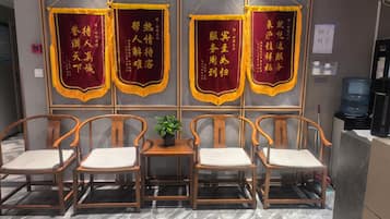 Un espace détente avec des chaises en bois et une petite table, un distributeur d’eau et un panneau avec des caractères chinois.