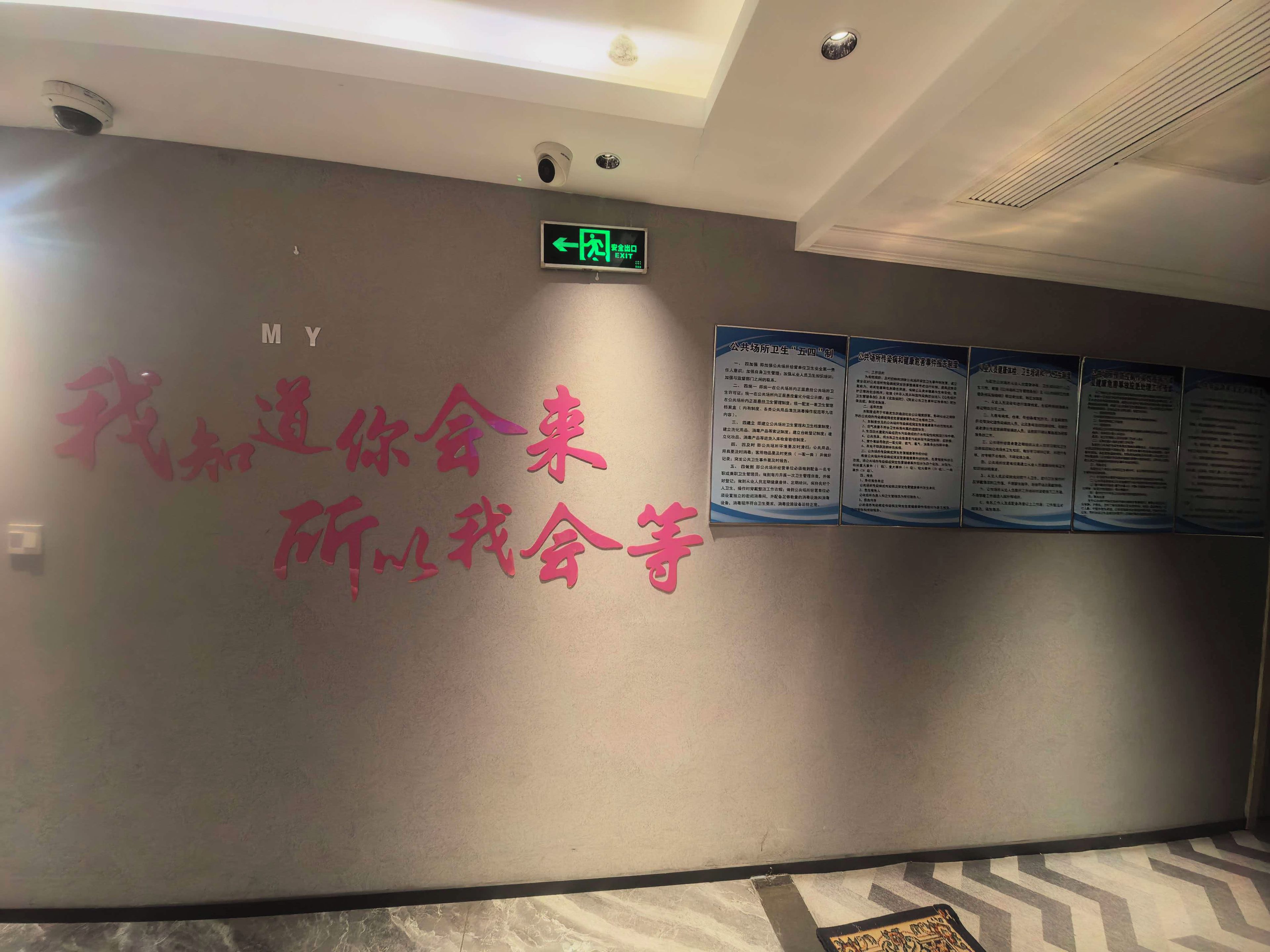 A wall with a sign indicating an exit and several informational posters.