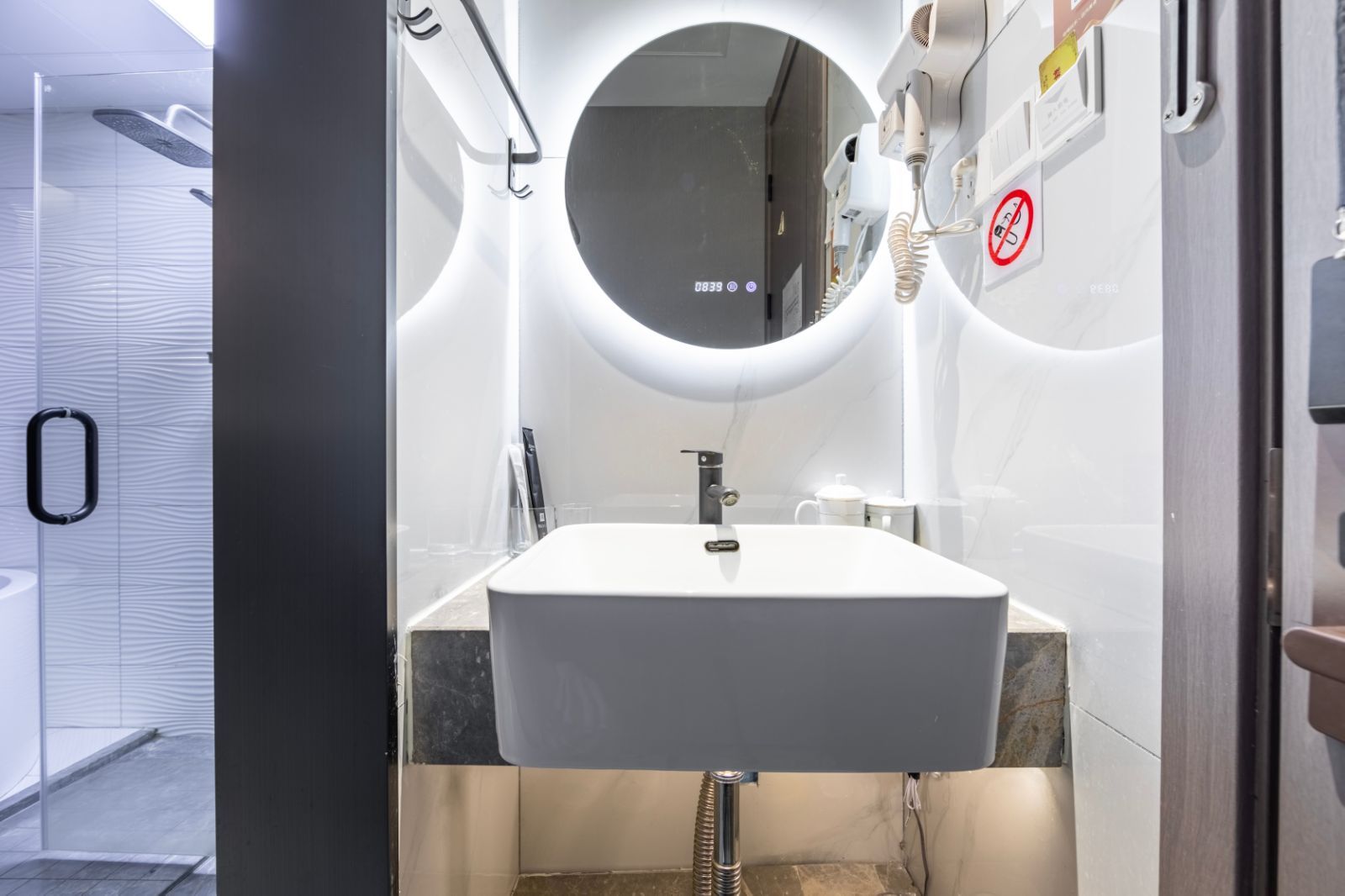 Une salle de bain moderne avec un lavabo blanc, un miroir rond et un porte-serviettes.