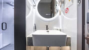 Une salle de bain moderne avec un lavabo blanc, un miroir rond et un porte-serviettes.