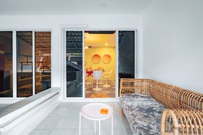 A modern living space with a sofa, a small table, and a dining area visible through a glass door. - RetroVibes An unique 9 pax house 500M BTS Iconsiam, Asiatique, Chao Phraya river (Krung Thep Maha Nakhon)