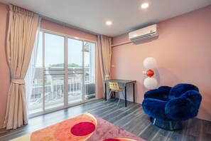 A modern room with a large sliding glass door, a blue chair, a small table, and a ceiling-mounted air conditioner. - RetroVibes An unique 9 pax house 500M BTS Iconsiam, Asiatique, Chao Phraya river (Krung Thep Maha Nakhon)
