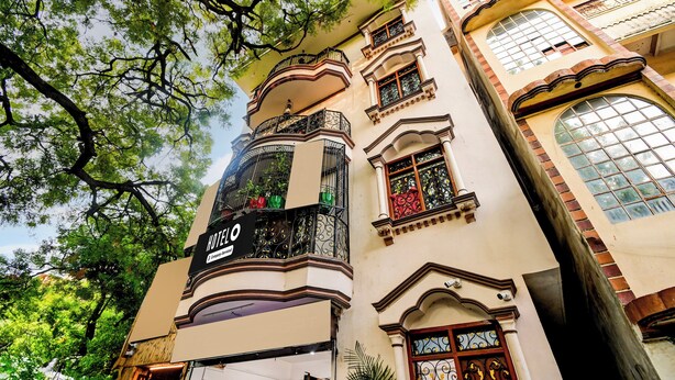 Un hôtel reconnaissable à son grand panneau « HÔTEL », à ses balcons richement décorés et à ses grandes fenêtres.