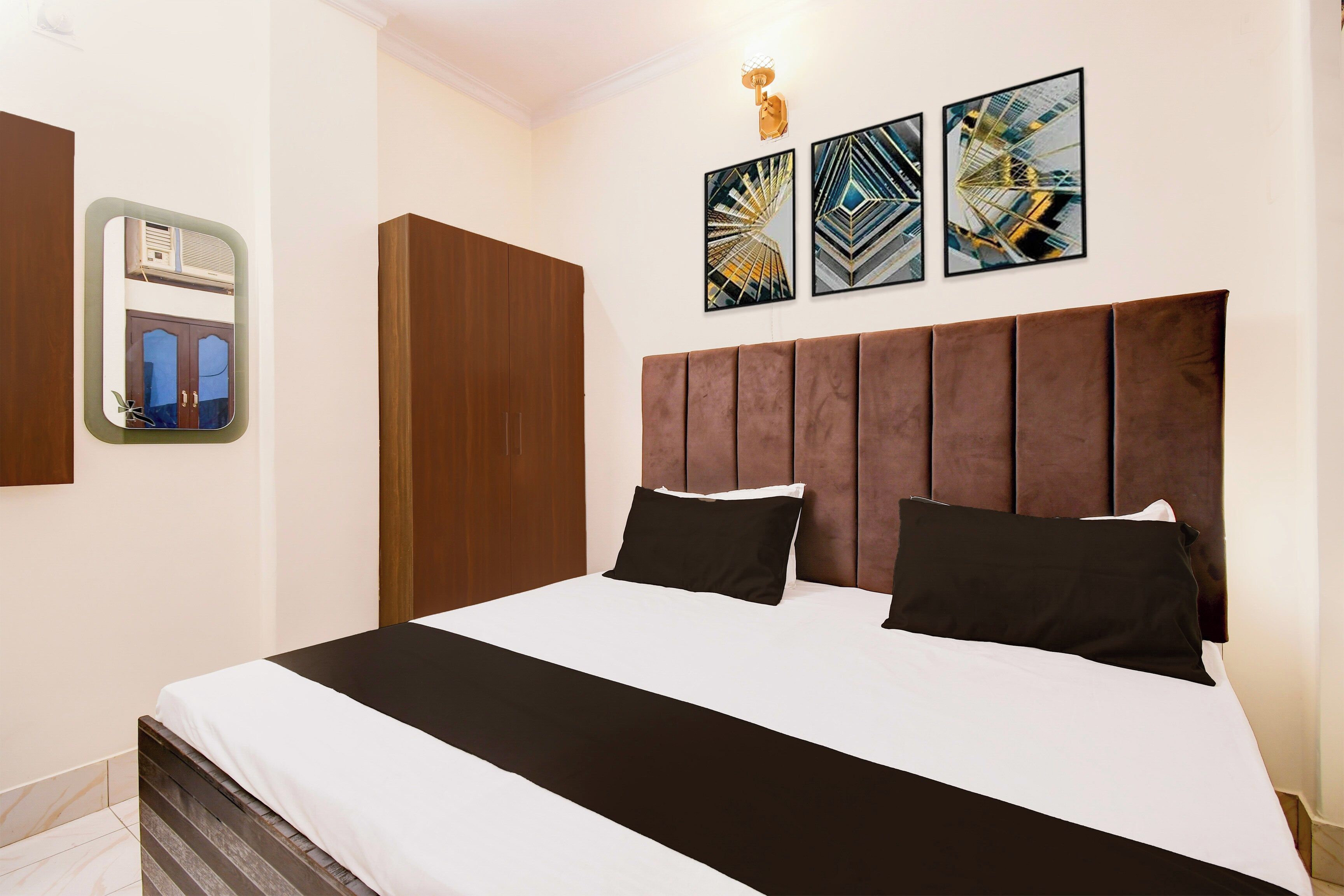 Quarto de hotel com uma cama grande, um guarda-roupa, um espelho e três obras de arte na parede.