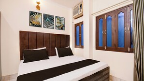 Une chambre d’hôtel comprenant un lit, une tête de lit, une fenêtre avec des rideaux et des œuvres d’art accrochées au mur.