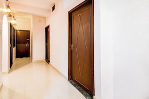 A hallway with two doors, one with a number plate, and a light fixture on the left. - Hotel O Benia Park Formerly Parv (Varanasi)