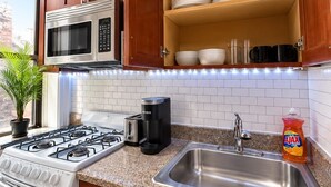 Une cuisine dotée de meubles en bois, d’un évier en acier inoxydable, d’un four à micro-ondes, d’une cuisinière et d’un lave-vaisselle.