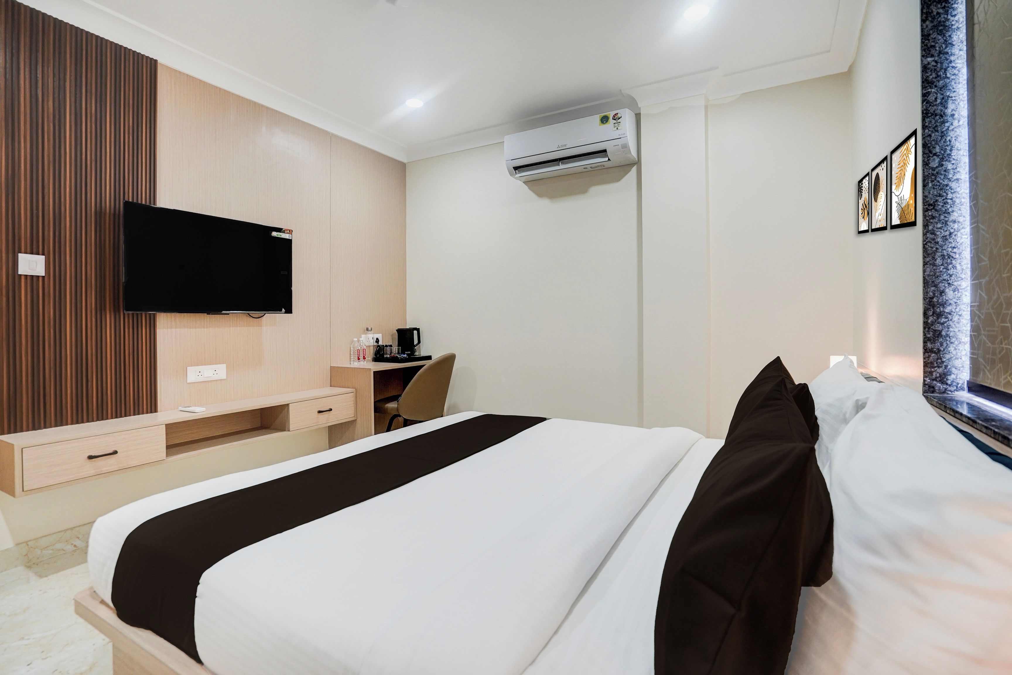 Een hotelkamer met een bed, een bureau, een airconditioner en een televisie.