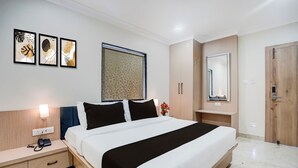 Une chambre d’hôtel comprenant un lit, des tables de chevet, une commode, une lampe fixée au mur, un miroir et une porte.