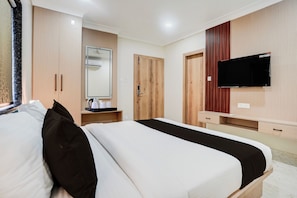 A hotel room with a bed, a TV, a wardrobe, and a mirror. - Super Townhouse Oak Banaras Central (Varanasi)