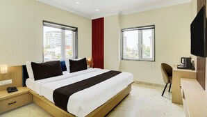 Une chambre d’hôtel comprenant un lit, des tables de chevet, un bureau avec une chaise et un téléviseur.