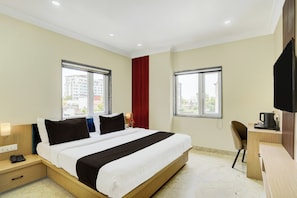 A hotel room with a bed, bedside tables, a desk with a chair, and a TV. - Super Townhouse Oak Banaras Central (Varanasi)