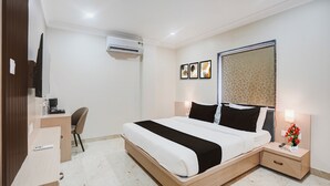 Une chambre d’hôtel équipée d’un lit, d’une table de chevet, d’un bureau, d’une chaise et d’un appareil de climatisation.