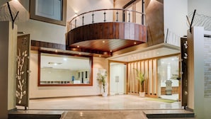 Un intérieur moderne avec un escalier en bois, un grand miroir et un espace d’accueil agrémenté d’une plante.