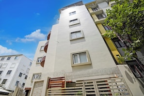 A multi-story building with balconies, a gated entrance, and a clear sky. - Super Townhouse Oak Banaras Central (Varanasi)
