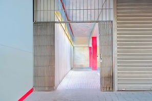 Un pasillo con una reja metálica, un pilar rojo y un cerrojo de metal cerrado.