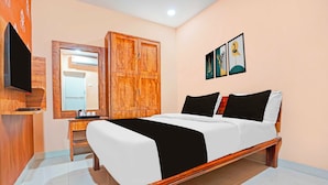 A bedroom with a bed, wooden wardrobe, a television, and artwork on the wall. - Collection O Dighori Nagpur (Nagpur)
