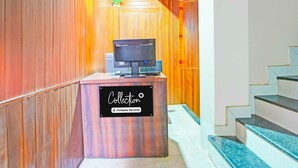 Un comptoir d’accueil avec une pancarte indiquant qu’il est à la disposition des employés de l’entreprise, un téléviseur et un escalier sur la droite.