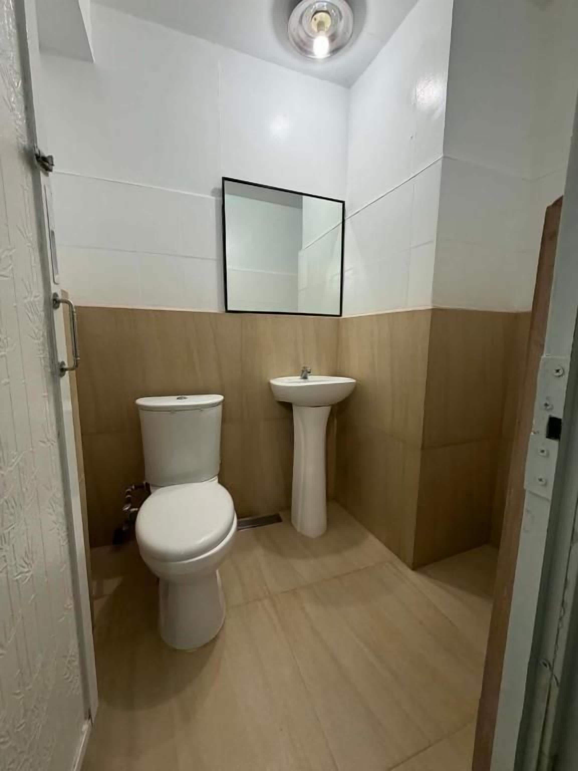 A bathroom with a toilet, sink, and mirror.