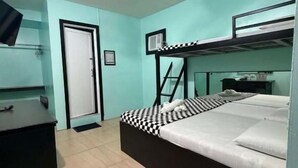 A room with a bunk bed, a desk, a chair, a fan, and a door. - We R Inn Hotel (Davao City)