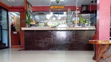 Un área de recepción con mostrador, un reloj y un cartel que indica la recepción.