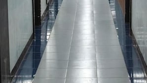 A corridor with a tiled floor, doors on both sides, and a fire extinguisher mounted on the wall.