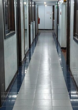 A corridor with a tiled floor, doors on both sides, and a fire extinguisher mounted on the wall.
