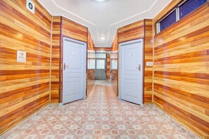 Un pasillo con paneles de madera y piso de baldosas, que conduce a dos puertas con números.