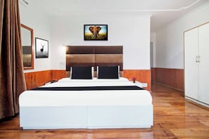 A bedroom with a large bed, a headboard, a nightstand, a mirror, and a picture of an elephant on the wall. - Collection O Srinagar Jhelum Riverside (Srinagar)