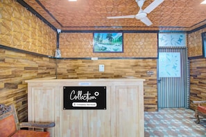Una recepción con un letrero que dice 'Collection Company-Serviced' en una habitación con paredes estampadas y un ventilador de techo.