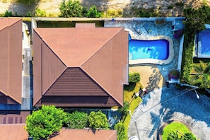 Um imóvel residencial com piscina, varanda coberta e jardim bem cuidado.