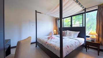 Uma cama de dossel com cortina, uma mesa de cabeceira com abajur e uma cadeira.