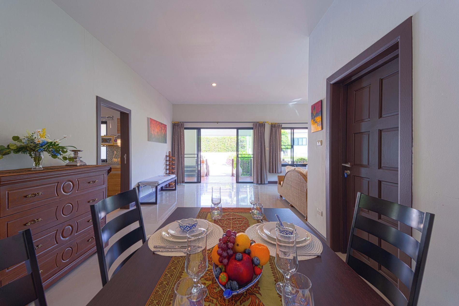 Uma área de refeições com mesa posta para quatro pessoas, um armário de madeira e vista para o exterior.