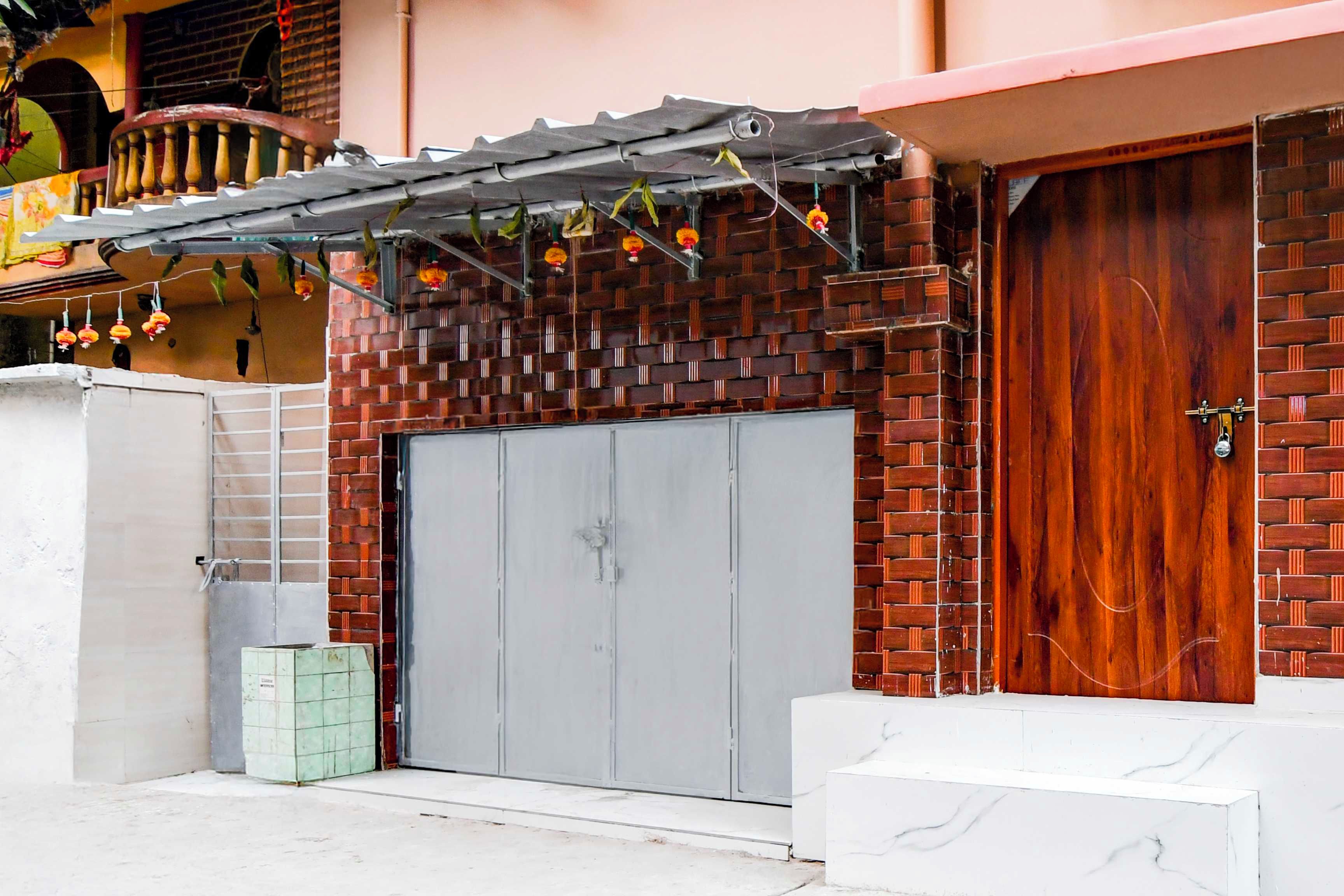 A building with a brick facade, a grey double door, and a wooden door.