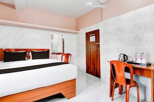 A hotel room with a bed, a desk, and a chair.