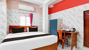 Quarto de hotel com cama, escrivaninha, cadeira e guarda-roupa.