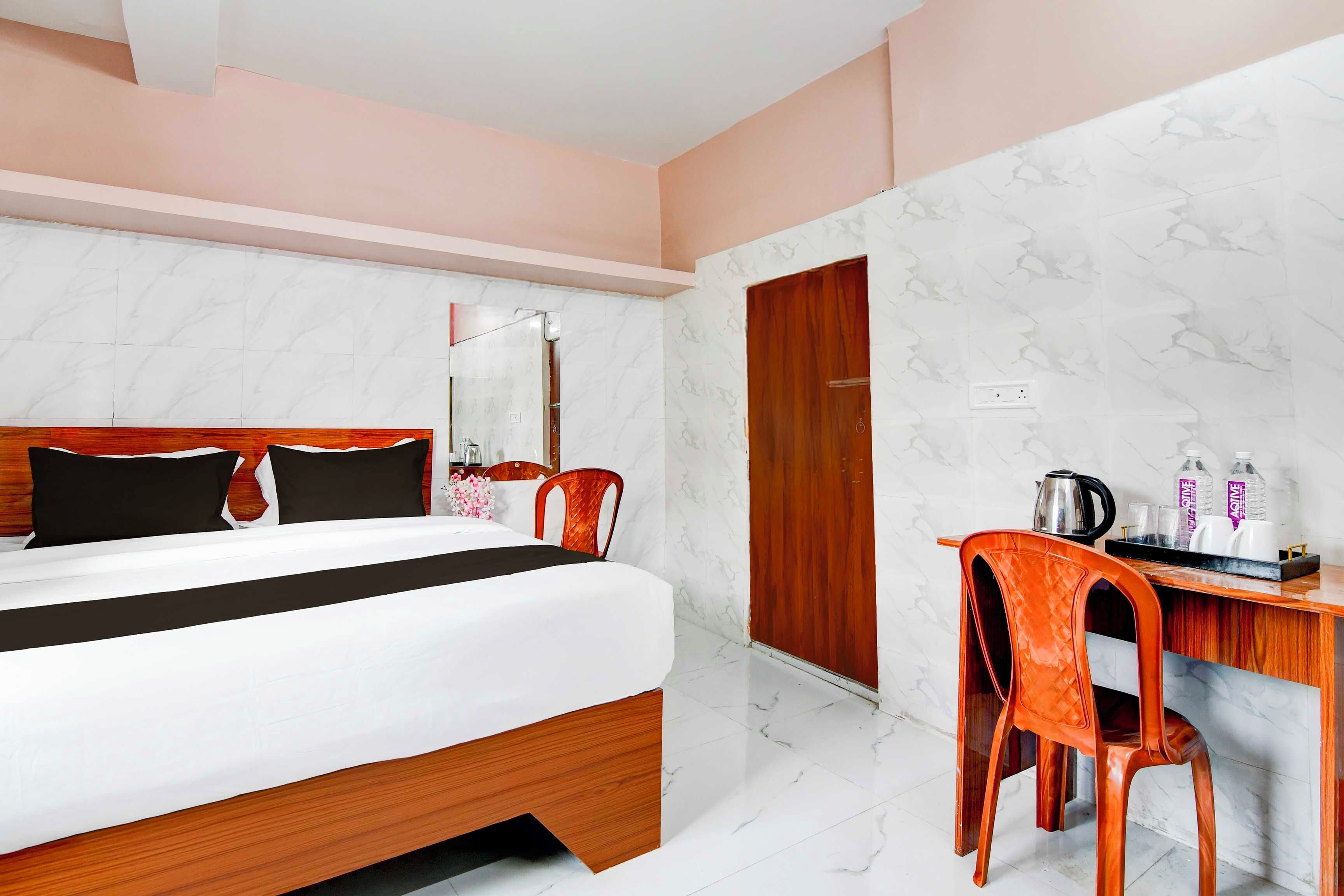 A hotel room with a bed, a desk, a chair, a mirror, and a wardrobe.
